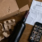 Livraison vin domicile : colis de vin abîmé, bouteille fissurée et étiquette de transport visible